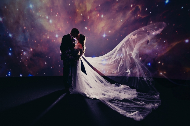 bride and groom kissing in front of space backdrop at Jodrell Bank Planetarium  