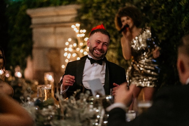 Gentleman wearing a black tux and party hat enjoying himself at Delamere Christmas party