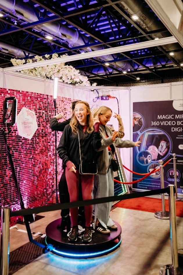 group of women trying out a 360 degree photo booth at a weddig show