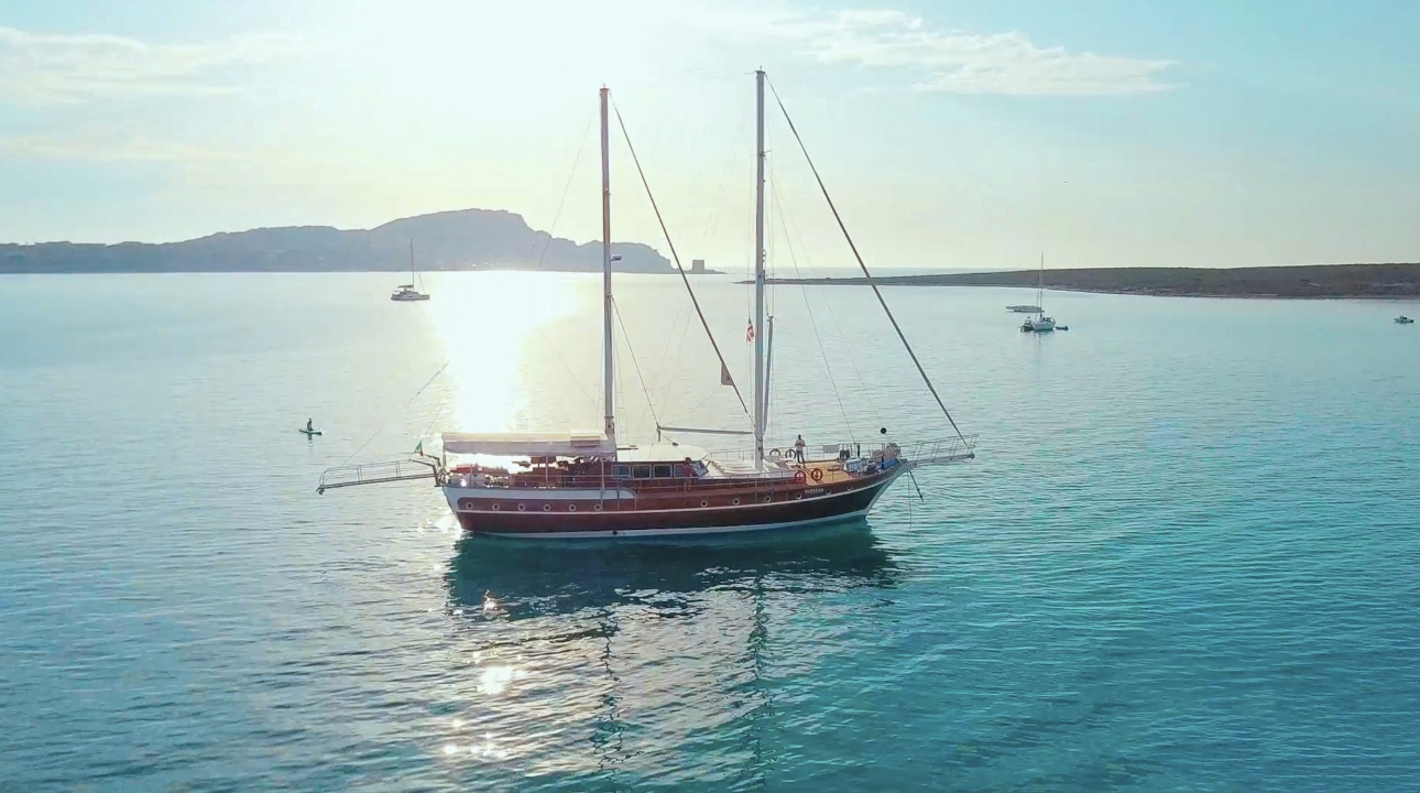 boast sailing on calm waters with smaller boats in background 